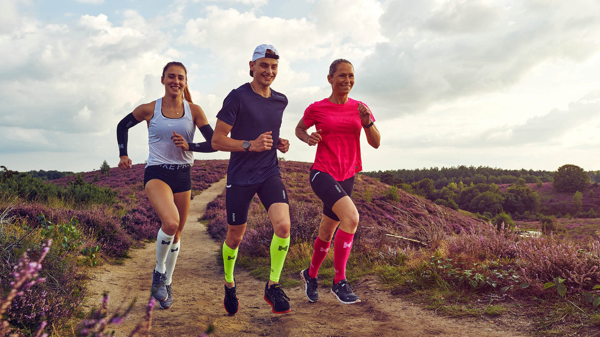 Herzog-Posbank 64 1920x1080 Three runners run across the flowering heather.
