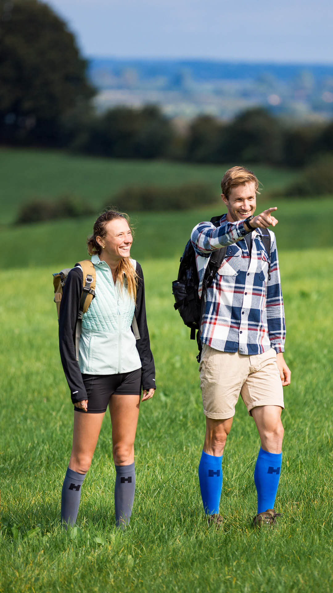 Sfeerbeeld Supportcompressiekousen Man en vrouw wandelen in een heuvelachtig weiland.